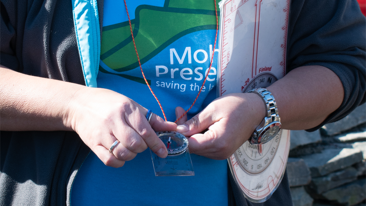 Mohonk Preserve Education staff hold a compass during San Miguel Orienteering