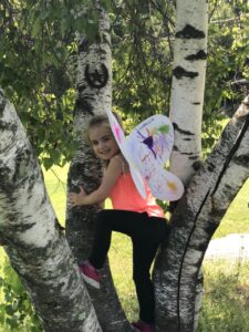 Camper with butterfly wings on in a tree 