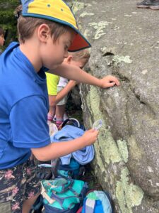 Camper using a hand lens to observe lichen on a rock