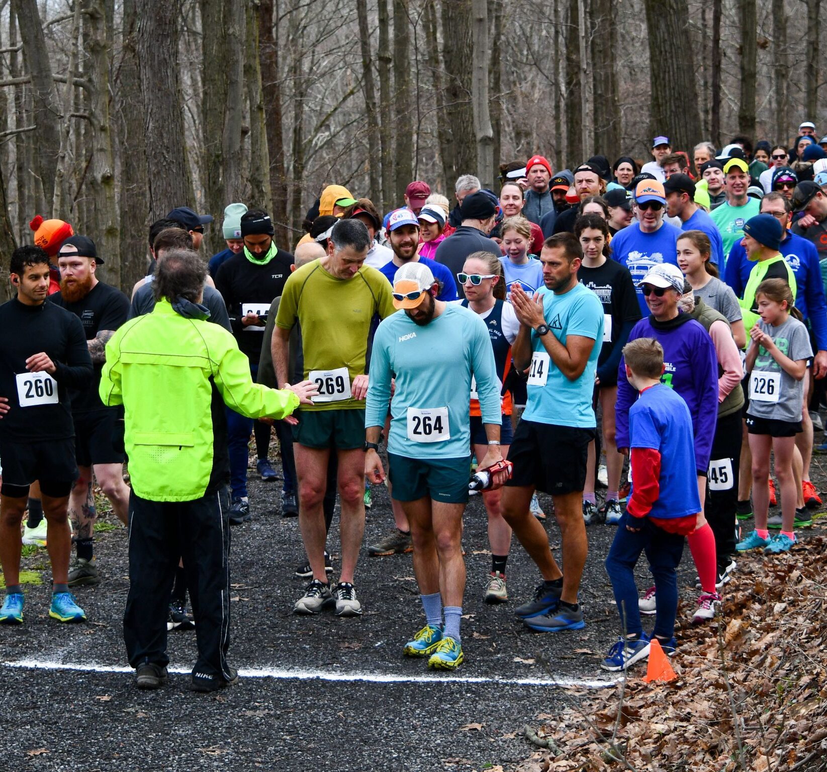 A group of runner at the starting line of Bridge 2 Bridge in a forested setting.